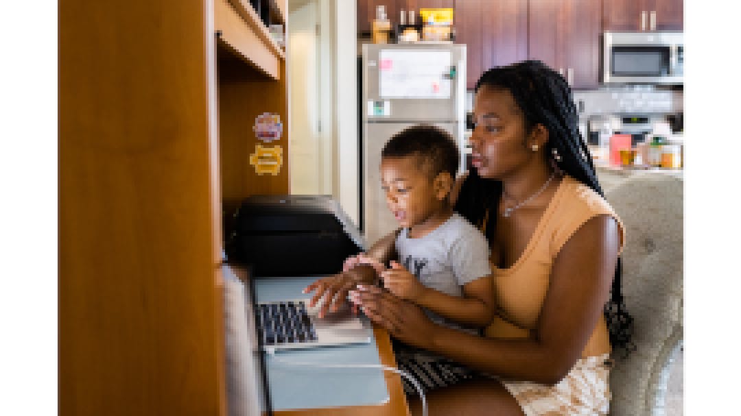 Sarah Turner and her son Noah sit at her desk in her apartment.